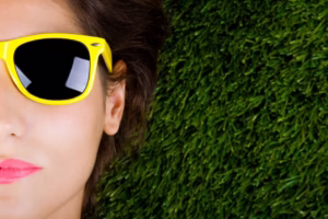 Mujer tumbada sobre la hierba con gafas de sol 300x200