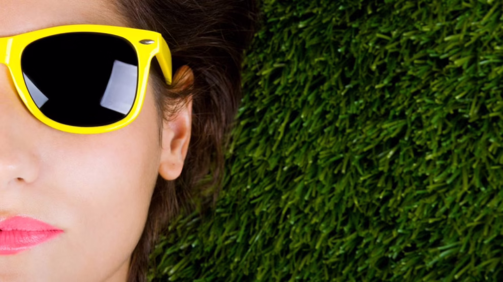 Mujer tumbada sobre la hierba con gafas de sol 990x556