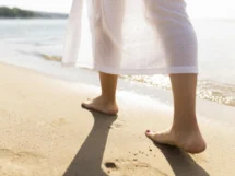 Back view woman s feet beach sands scaled 1 215x161