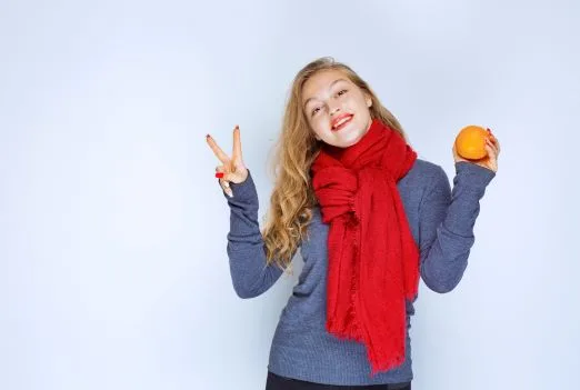 Blonde girl holding orange fruit enjoying taste jpg