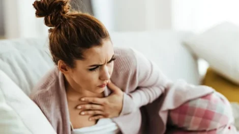 Distraught woman holding her chest pain while lying down sofa living room jpg 470x264