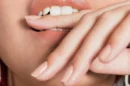 Ekstremalne zblizenie strzal mloda kobieta gryzac palec jpg 130x86