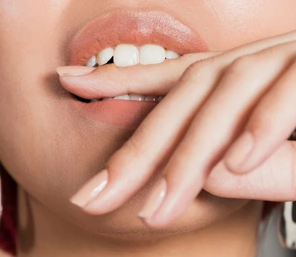 Ekstremalne zblizenie strzal mloda kobieta gryzac palec jpg