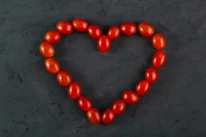 Pomidory czeresniowe czerwone w ksztalcie serca czerwone pomidory na ciemnym biurku scaled 1 300x200