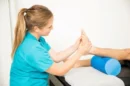 Profesjonalna kobieca fizjoterapia masujaca stope pacjenta w klinice jpg 130x86