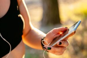 Sportowy kobieta w czarnej podkoszulek za pomoca telefonu komorkowego podczas sluchania muzyki 8353 6323 300x200