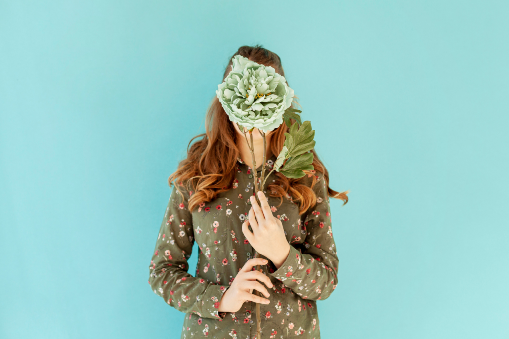 Female covering face with fresh flower 1024x682