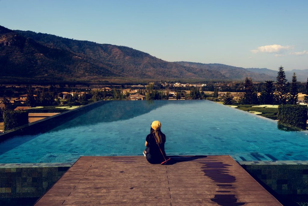 Woman sitting by poolside wiht mountain view 1024x683