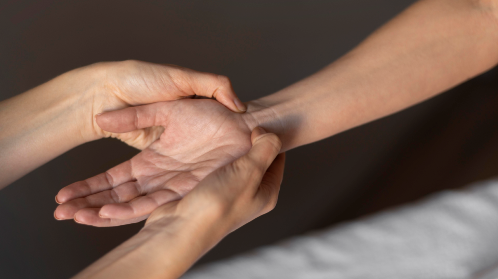 Close up hands massaging wrist 990x556