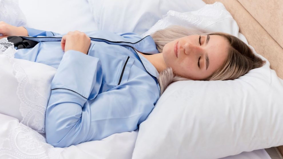 Young beautiful woman blue pajamas laying bed 990x556