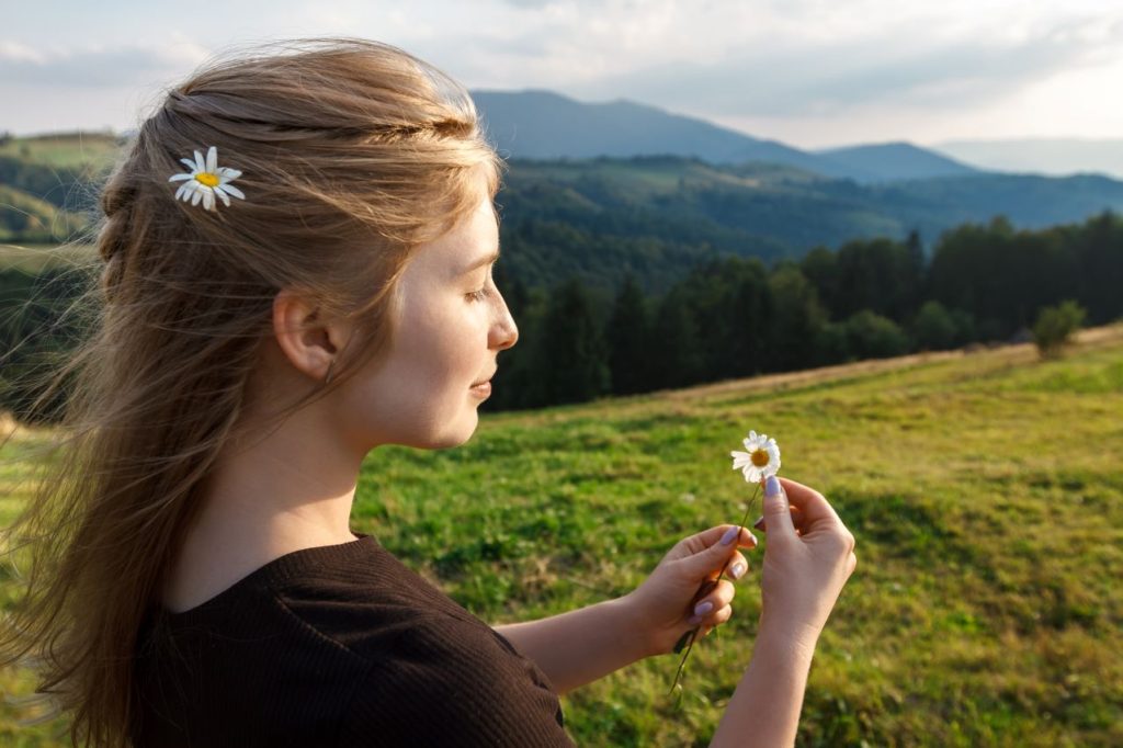 Beautiful blonde woman holding camomiles carpathian mountains background 1024x682