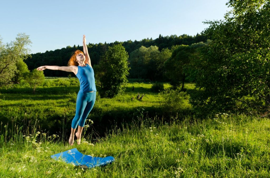 Red woman practicing fitness yoga outdoors 1024x678