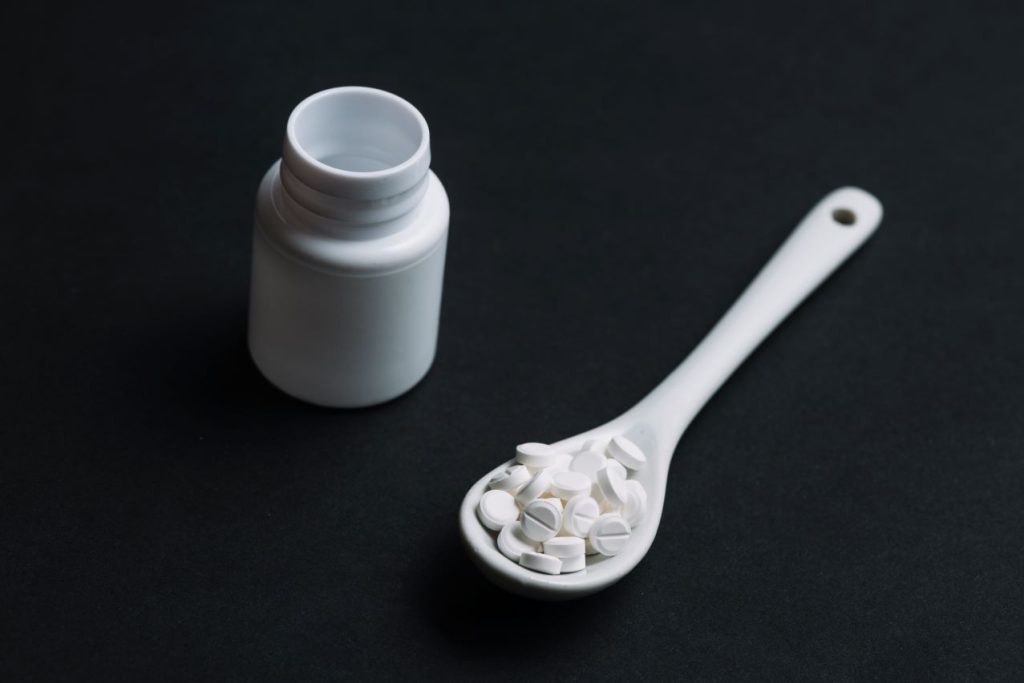 White pills spoon plastic bottle 1024x683