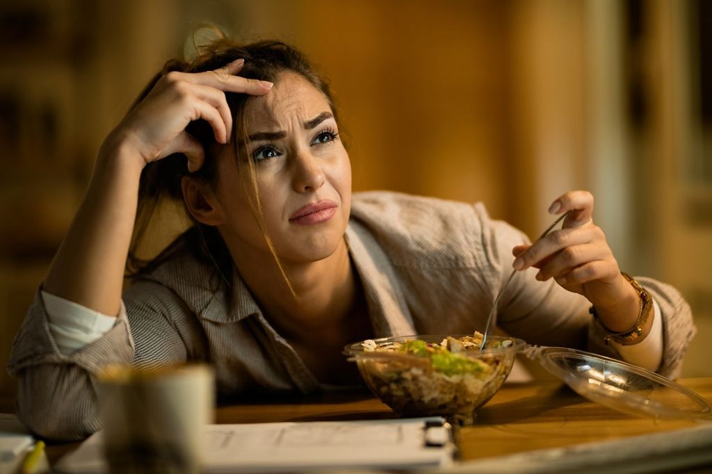 Displeased woman feeling confused while reading email computer eating salad night 1024x682