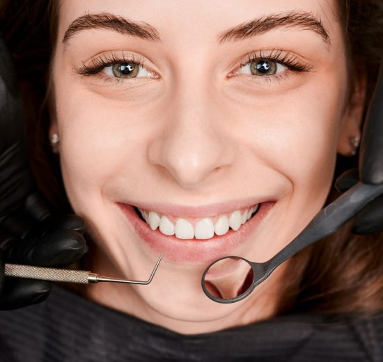 Cheerful young woman having dental examination clinic 550x520