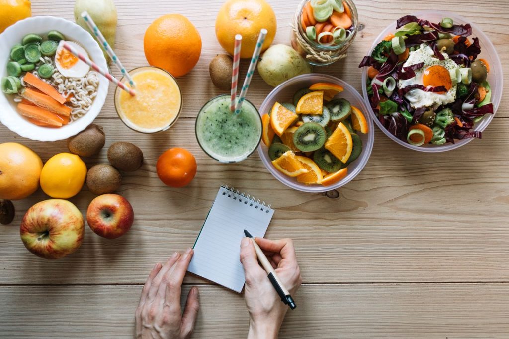 Crop hands writing near healthy food 1024x682