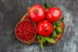 Top close up view pomegranates three pomegranates pomegranate seeds cutting board 300x200