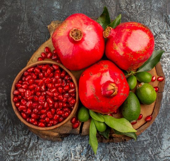 Top close up view pomegranates three pomegranates pomegranate seeds cutting board 550x520